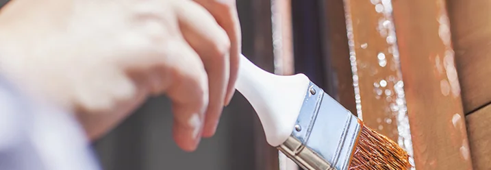 Hand streicht Holz braun